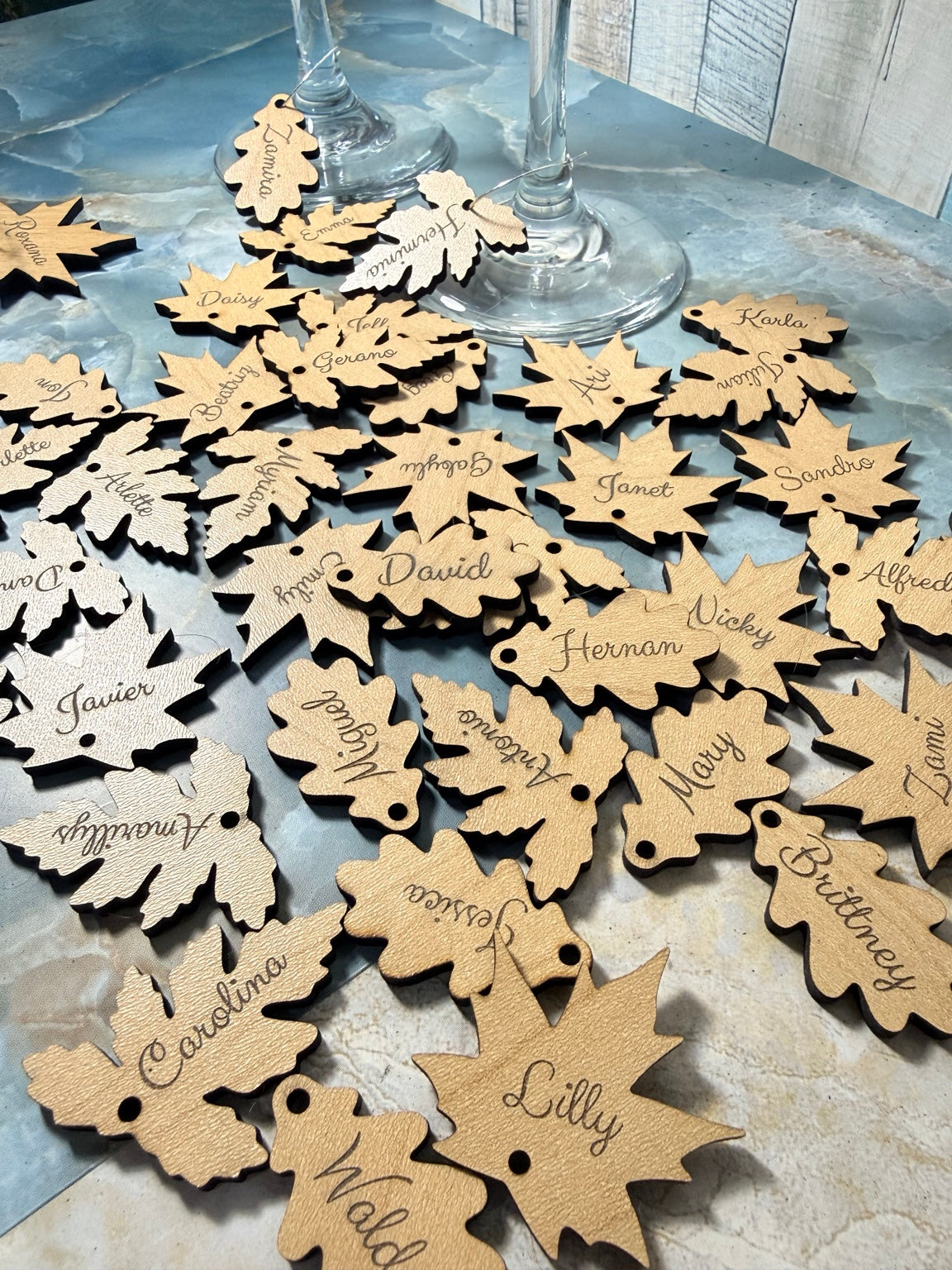Assorted engraved wooden leaf charms beside wine glasses