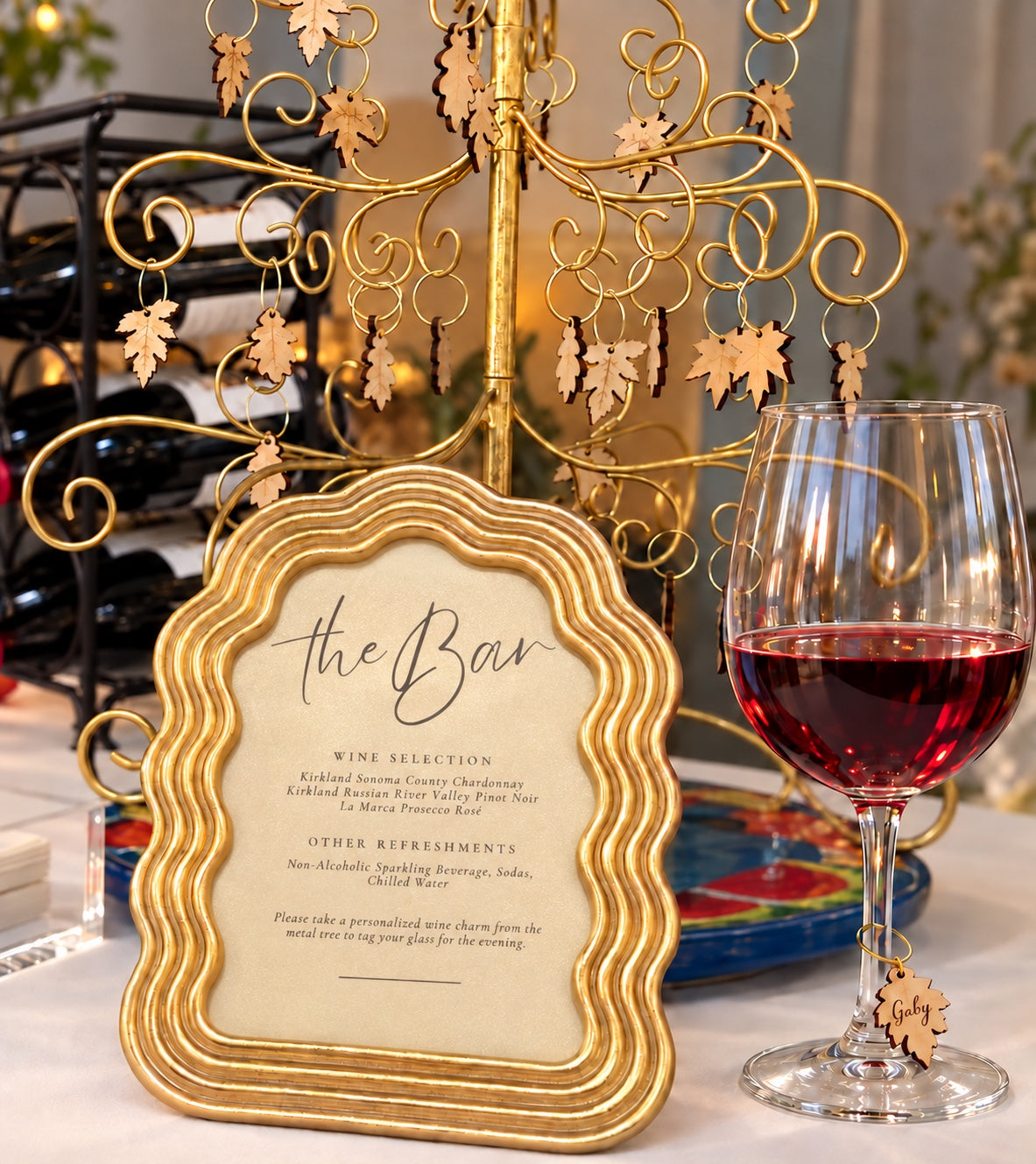Personalized leaf wine charm on a wine glass beside a decorative bar display