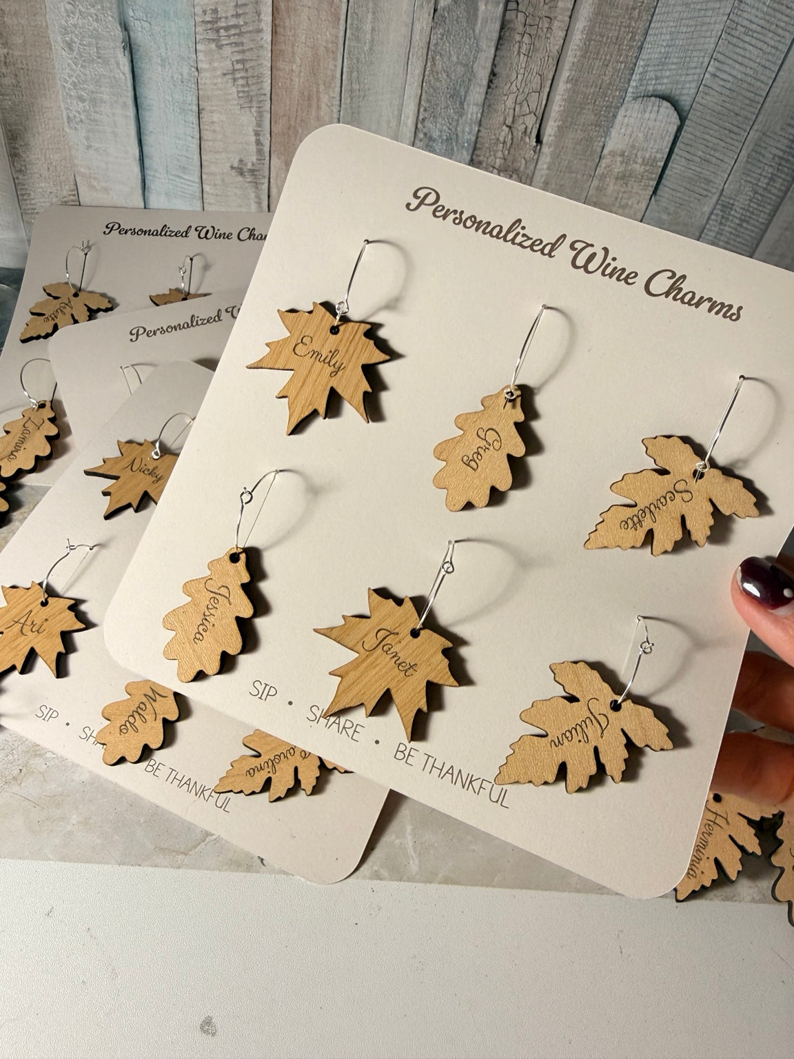 Mixed personalized wooden leaf wine charms on presentation cards
