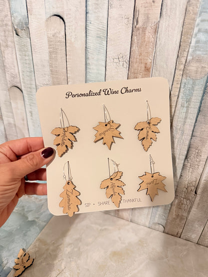 Six wooden leaf wine charms personalized with guest names