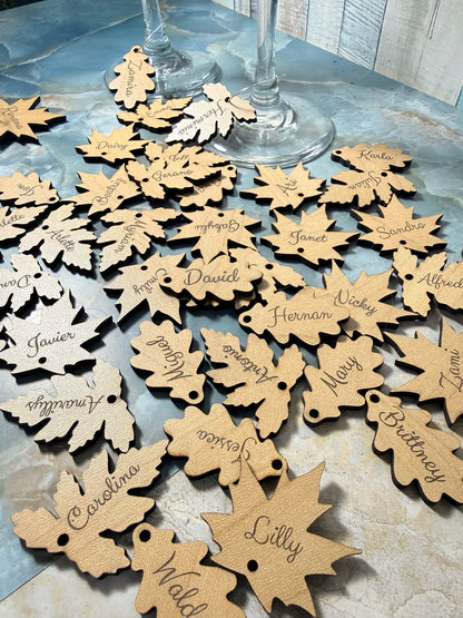 Assorted engraved wooden leaf charms beside wine glasses
