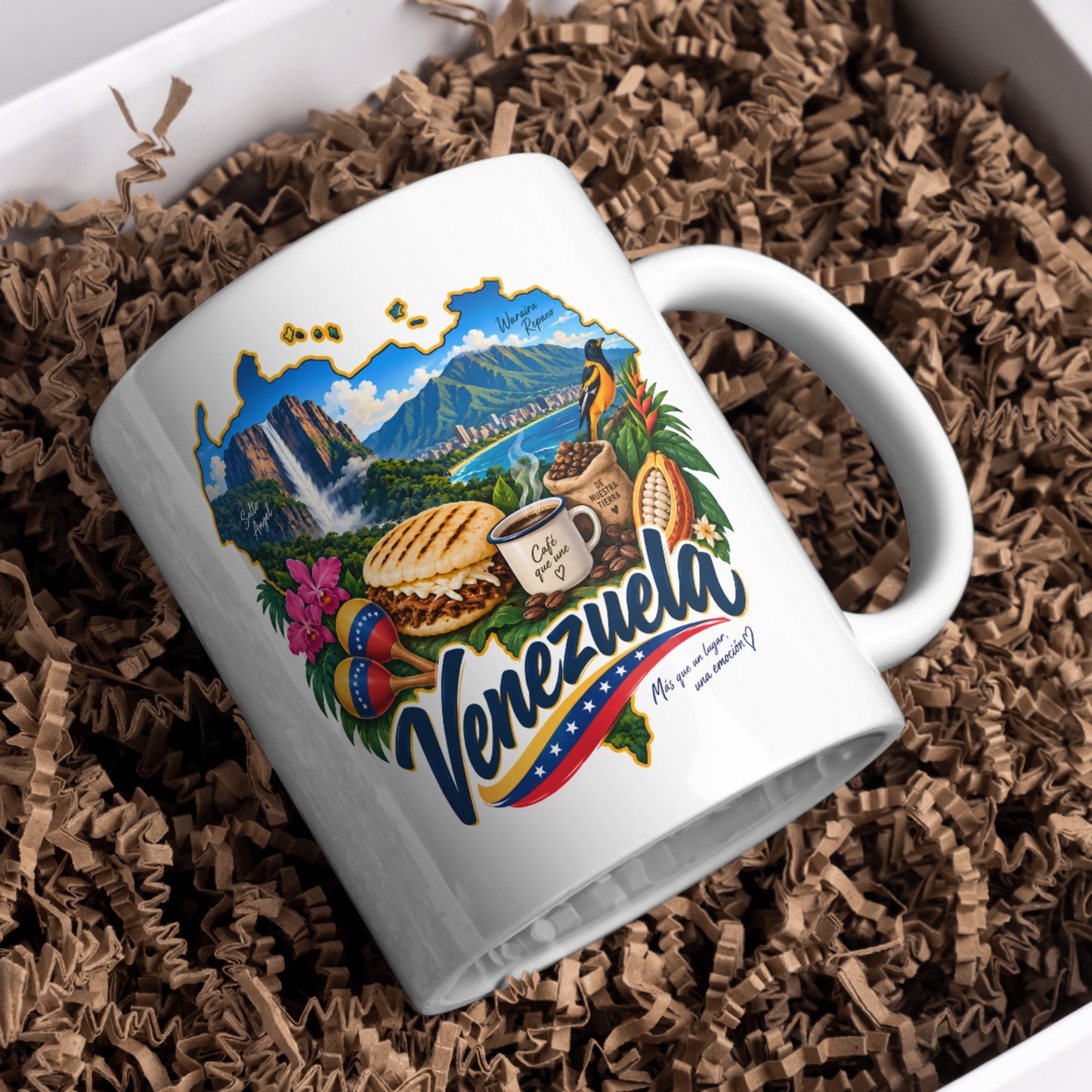 White ceramic Venezuela mug displayed in gift box filler with colorful Venezuela-inspired artwork.