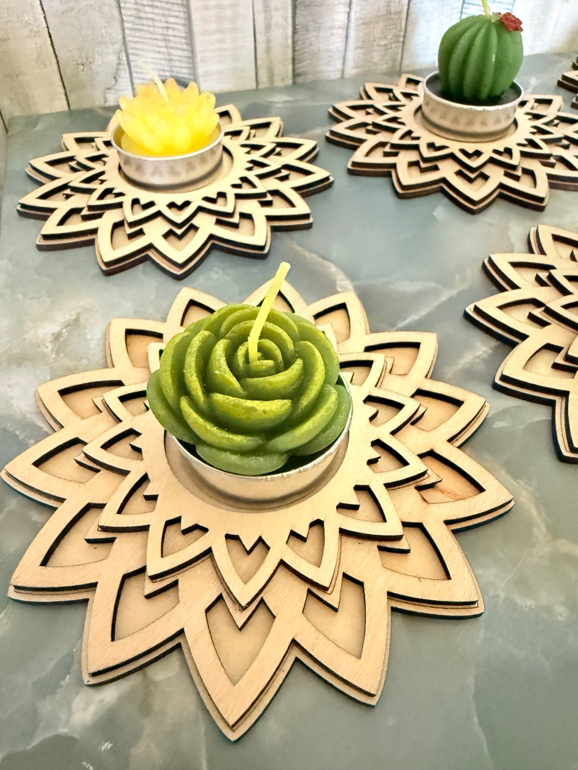 Close-up of a green succulent-shaped candle in a layered wooden mandala holder; succulent upgrade costs $1.50 extra
